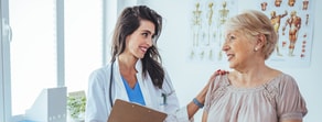 In a digitally advanced exam room, a medbridge professional smiles warmly at an older woman.