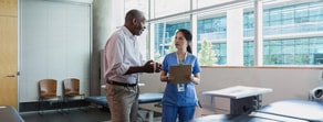 A nurse with a clipboard and a man discuss healthcare training in a bright room associated with medbridge.