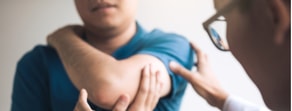 A healthcare professional examines a patient's arm, highlighting digital healthcare's role in modern care, with medbridge playing a part.