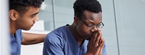 Two healthcare professionals in blue scrubs demonstrate empathy, a key element of medbridge education.