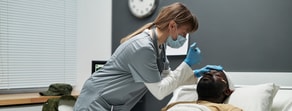 A nurse in scrubs and a mask provides attentive care to a patient, embodying Medbridge’s commitment to healthcare education.
