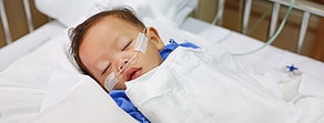 A baby with a nasal cannula sleeps in a hospital crib, showcasing digital healthcare like medbridge.