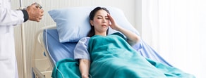 A patient rests in a hospital bed while a healthcare worker uses a digital device, highlighting medbridge technology.