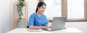 A person in blue scrubs studies digital healthcare on a laptop beside a clipboard, with blinds and a plant adding calmness—highlighting medbridge education.