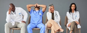 Four exhausted healthcare professionals in medical uniforms sit against a gray wall, illustrating the demands of medbridge training.