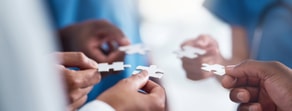 Diverse hands holding puzzle pieces symbolizing teamwork in Medbridge hybrid care.