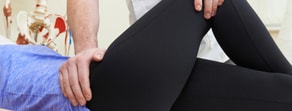 A therapist aids a hip stretch during a physical therapy session, showcasing medbridge techniques.