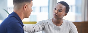 A woman with short hair consoles a man in a blue shirt as they discuss digital healthcare solutions from medbridge.