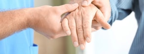 A healthcare worker holds an elderly hand, highlighting compassion with medbridge's digital solutions.