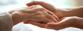 A young person holds an elderly person's hand, showing care and connection through medbridge's hybrid solutions.