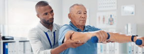 In a clinic, a man helps a senior with dumbbell exercises, highlighting healthcare education's role.