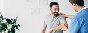 A health professional uses Medbridge software to assess a patient's shoulder and arm.