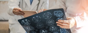 Two doctors review a brain MRI scan and tablet with medbridge.
