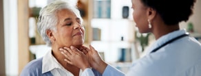 A doctor checks an older woman's throat in a medbridge office.