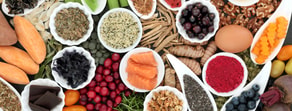 A variety of superfoods such as salmon, berries, seeds, nuts, spices, and vegetables in bowls and plates.