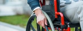 A person in a wheelchair wearing a blue jacket and beige pants.