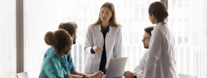 Five healthcare professionals meet around a table with a laptop, discussing medbridge education.
