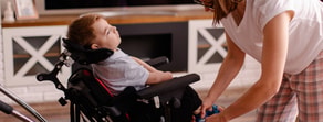 A woman adjusts a young boy's shoe in a wheelchair during medbridge healthcare training.