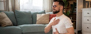A man practices deep breathing exercises in his living room as part of medbridge digital healthcare education.