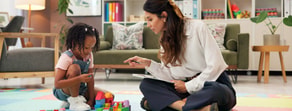 A woman with a clipboard observes a young girl building blocks in a living room, representing medbridge healthcare education.