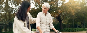 An elderly woman with a walker and a younger woman stand outside in light jackets, promoting medbridge healthcare education.