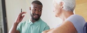 A man with a pen talks about healthcare training with a woman with short white hair in a casual medbridge setting.