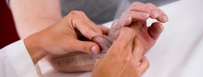 One person measures another’s finger with a transparent goniometer on a white surface for medbridge digital assessment.