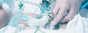 A gloved hand uses a stethoscope on an intubated patient with medical tubes in a hospital, showing medbridge healthcare training.