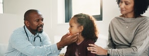 A healthcare professional examines a young girl’s throat as her mother sits beside her in a medbridge medical office.