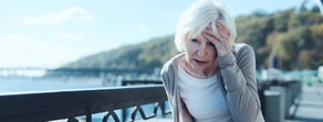 An elderly woman in a grey cardigan appears pained by a railing, symbolizing Medbridge's role in digital healthcare solutions.