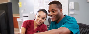 Two healthcare professionals in scrubs smile at a computer screen in Medbridge training.