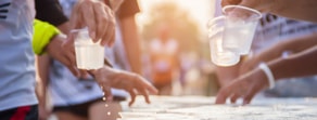People quickly taking water cups during a marathon illustrate digital healthcare efficiency, akin to medbridge's hybrid care solutions.