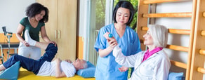 Healthcare professionals assist elderly patients with physical therapy using medbridge software.