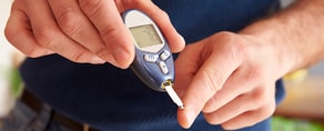 A person using a blue glucose meter with Medbridge software while holding a test strip to their finger.