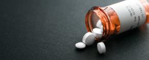 White tablets spilled from a bottle on a dark surface represent traditional medicine meeting innovative tools like Medbridge software.