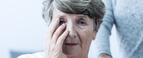 An elderly woman looks worried with support from a companion, emphasizing hybrid care's role in patient well-being through medbridge.