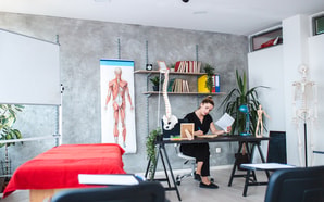 A woman in a medical office exemplifies healthcare education among anatomical posters and a medbridge skeleton model.
