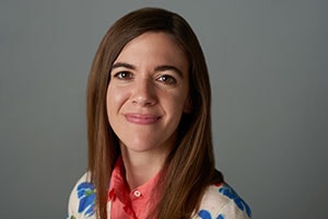 A smiling woman in a floral jacket and coral shirt represents medbridge's dynamic healthcare education.