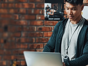 A person uses a laptop in a brick-walled room with medbridge posters.