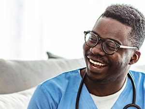Home health clinician smiling and speaking with an older adult patient, representing patient satisfaction in home health care.