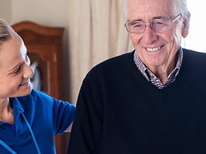 Home health provider supporting an older adult during a visit, representing CMS 2023 home health final payment rule updates.