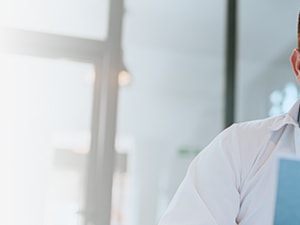 A person with glasses is thoughtfully examining a paper indoors.