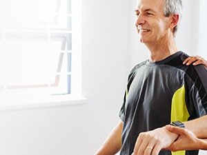 A woman helps a man with arm exercises in a well-lit room, using medbridge.