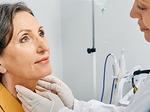 A healthcare professional examines a patient's neck in a medbridge room.