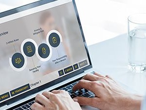 Person using a laptop showing a medbridge dashboard with circular graphics, next to a water glass and lamp on a desk.