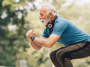Older adult performing a squat exercise outdoors, demonstrating physical activity for knee osteoarthritis management.