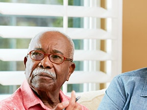 Healthcare provider speaking with an older adult patient and family caregiver at home, emphasizing communication in hospice care.