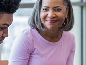 A woman smiles at a young person in a bright room during a medbridge session.
