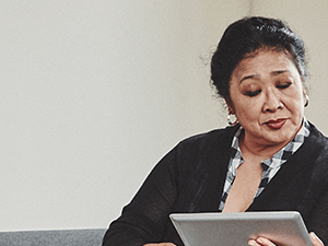 Two women, a Medbridge professional in uniform and another in a black cardigan, sit on a couch looking at a tablet.