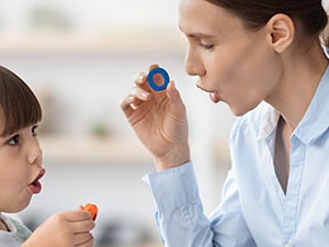 Speech-language pathologist practices speech sounds with a young child using bubbles during a childhood apraxia of speech session.